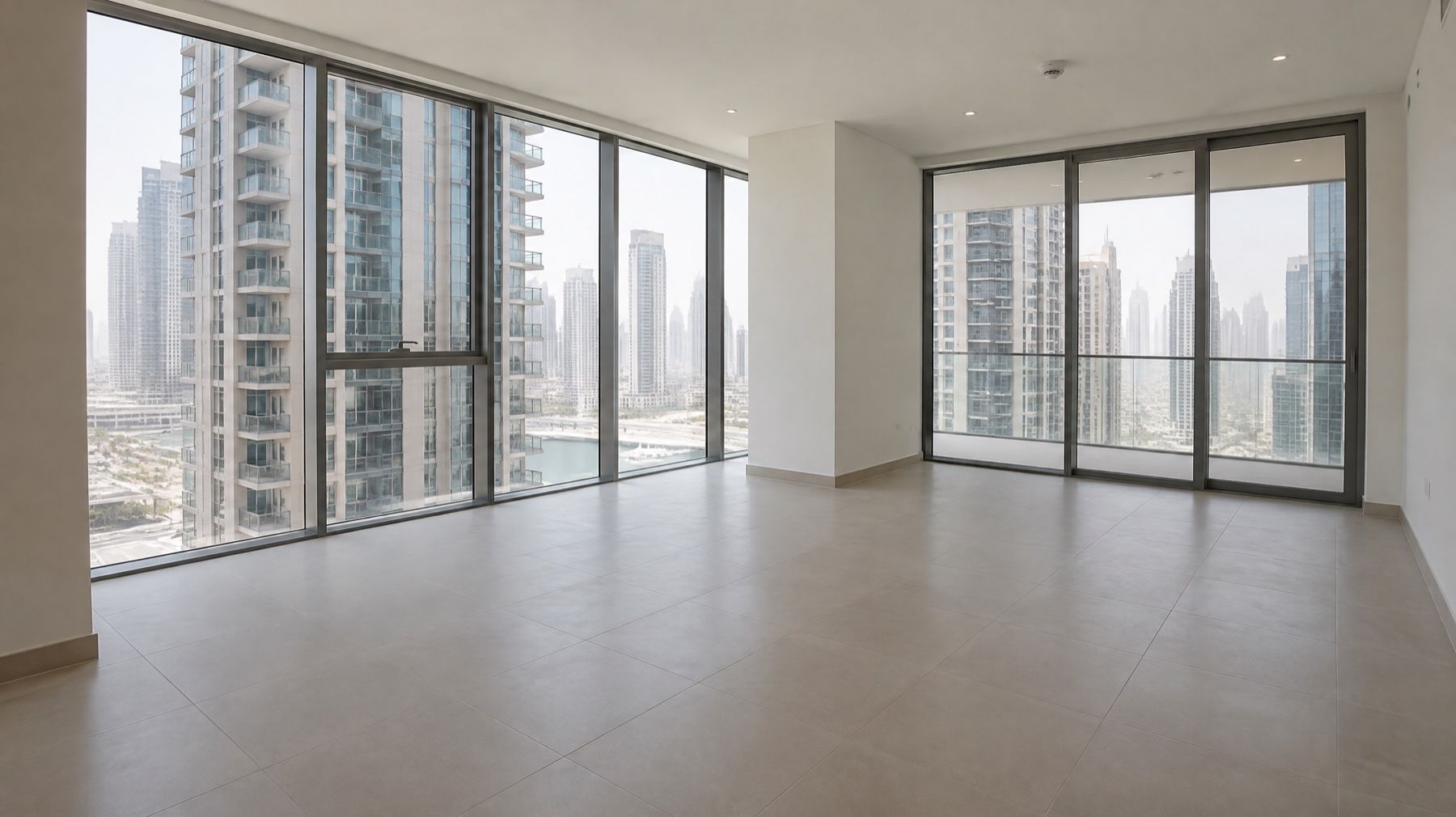 An empty new apartment living room with floor-to-ceiling windows and towers outside.
