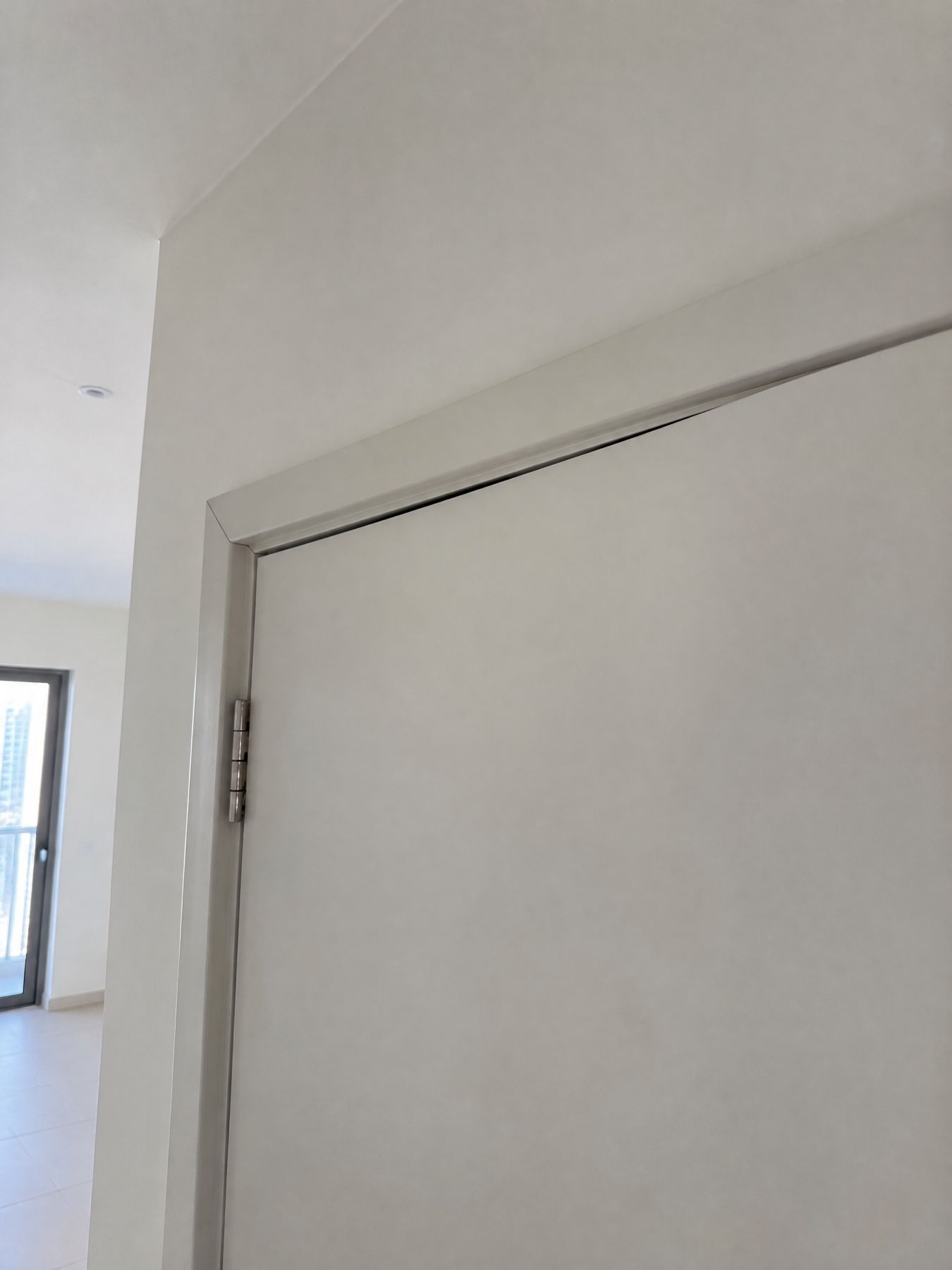 The top corner of an interior door with an uneven gap between the door and its frame.